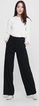 Model met zwarte wijde broek, met knoopdetail, gedragen met witte top.
