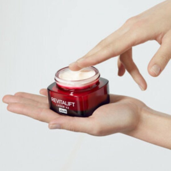Hand die crème uit een rood potje haalt, L'Oréal Paris Revitalift Laser X3.