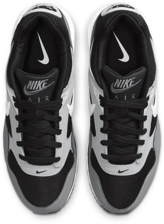 Bovenkant van zwarte Nike sneakers met grijze en witte details. Nike 'swoosh' en 'Air' logo's zichtbaar op de tong.