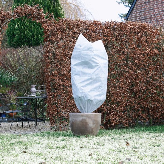 Witte winterhoes om een plant in een pot in een tuin.