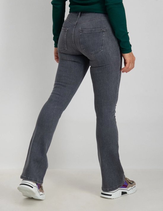 Model van achteren gezien in grijze flared jeans met sneakers.