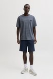 Man in een donkerblauw, gemêleerd T-shirt met korte mouwen en marineblauwe shorts.