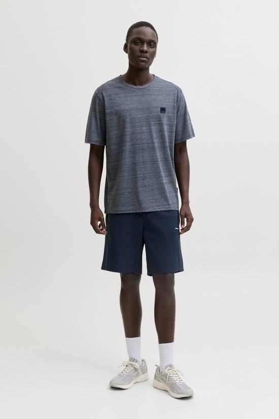 Man in een donkerblauw, gemêleerd T-shirt met korte mouwen en marineblauwe shorts.