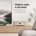 Gouden audiospeler met knoppen en scherm, naast een TV. "Heldere audio. In elk detail."