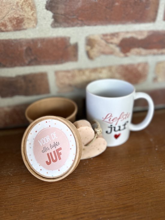 Ronde doos met de tekst "Voor de aller liefste juf", naast een mok en hartvormige zeep. De doos is half geopend.