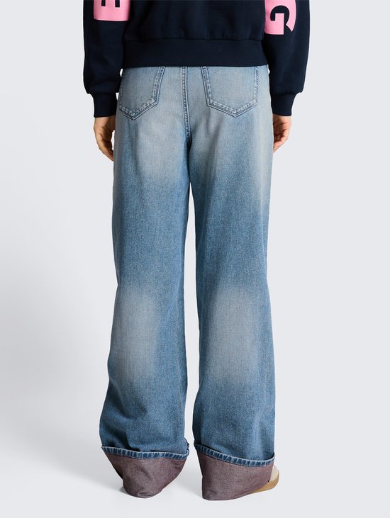 Achterkant van een wijde, lichtblauwe jeans met omgeslagen zoom.