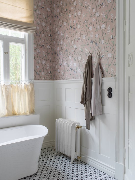Badkamer met roze bloemenbehang, een vrijstaand bad en een radiator.