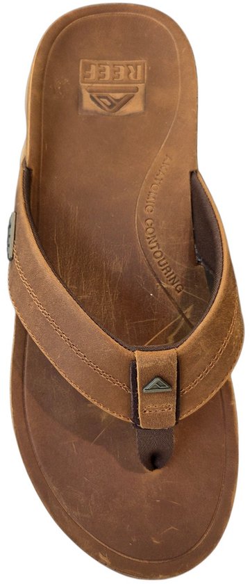 Bovenaanzicht van een bruine Reef teenslipper met leren bandjes. De Reef logo's zijn zichtbaar.