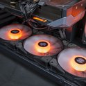 Drie ventilatoren met oranje verlichting aan de onderkant van een gaming pc, met zicht op de grafische kaart.