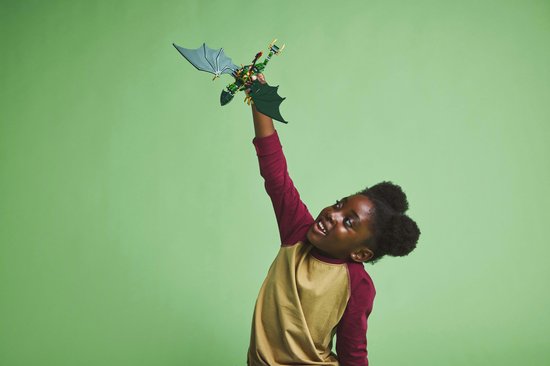 Meisje met afro-kapsel houdt een groene LEGO draak met gespreide vleugels omhoog.
