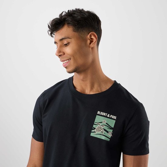 Man met zwarte t-shirt met schildpaddenprint, met groene tekst 'BLOUNT & POOL' en kleine schildpadjes.