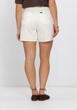 Zijzicht van een vrouw in een witte spijkerbroekshort met wijde pijpen en de achterkant zichtbaar.