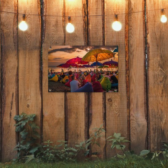 Tuinposter 60x40 cm - Tuindecoratie Toeristen genieten van de zonsondergang bij het strand van Denpasar in Bali, Indonesië - Poster voor in de tuin - Buiten decoratie - Schutting tuinschilderij - Tuindoek muurdecoratie - Wanddecoratie balkondoek
