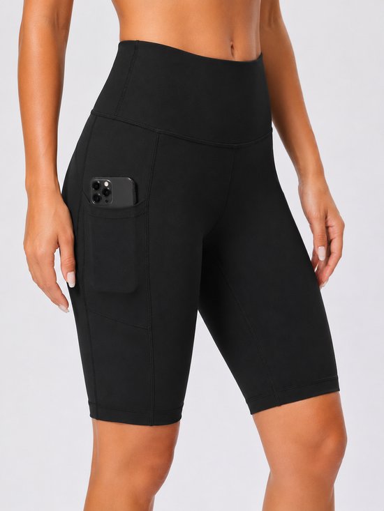 Zwarte sportshort met hoge taille en zak aan de zijkant met daarin een smartphone.