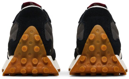 Achterkant van twee zwarte New Balance sneakers met bruine, noppen-achtige profielzolen.