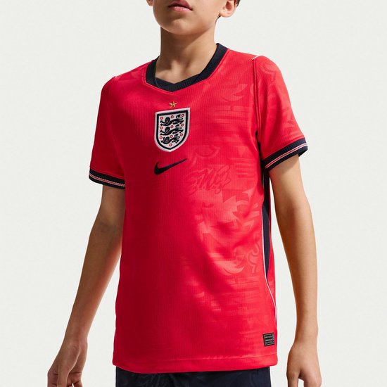 Jongen in rood shirt met een opdruk en een Nike logo. Shirt heeft een donkerblauwe kraag.