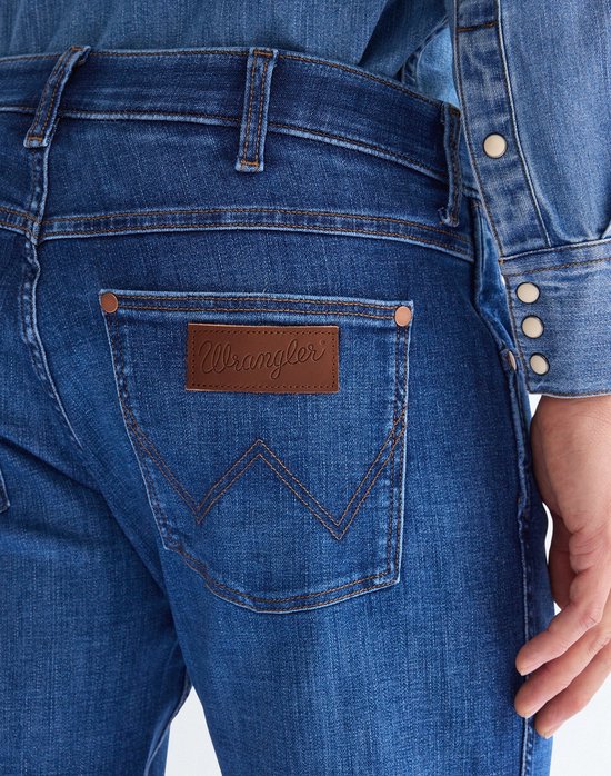 Achterkant van blauwe Wrangler jeans met bruin leren merklabel.