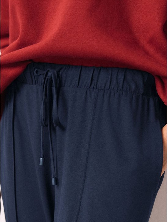 Close-up van de tailleband en trekkoord van een donkerblauwe joggingbroek.