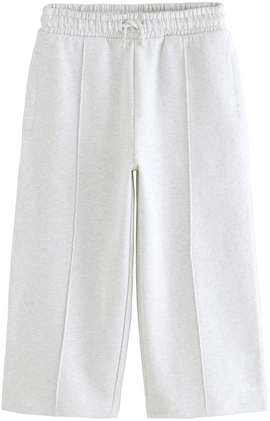 Lichtgrijze wijde joggingbroek met deelnaden, elastische tailleband en trekkoord, op witte achtergrond.