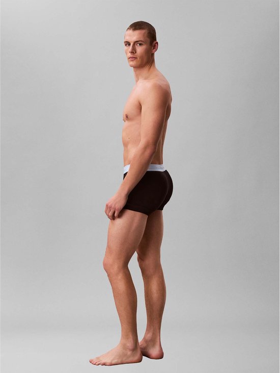 Man met bruine boxershorts met grijze Calvin Klein band, profiel naar links.
