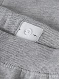 Detail van een verstelbare tailleband met knoop van een grijze joggingbroek.