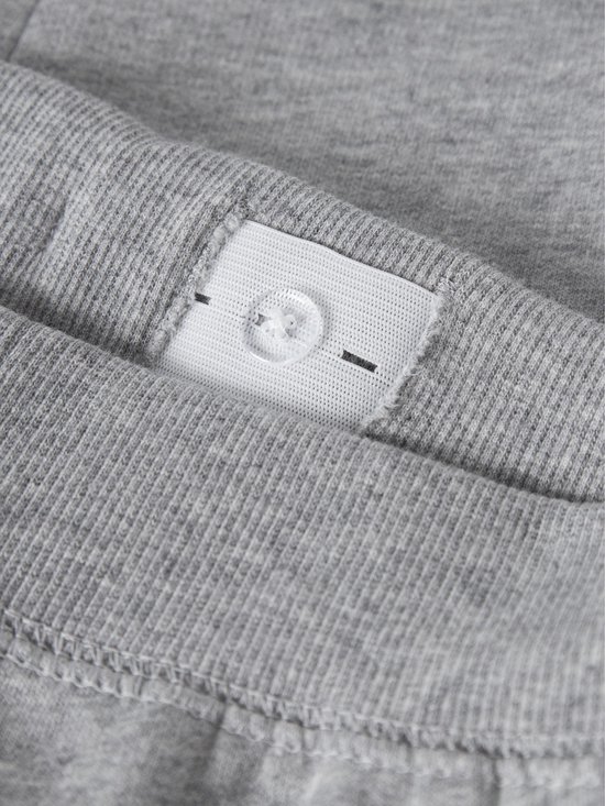 Detail van een verstelbare tailleband met knoop van een grijze joggingbroek.