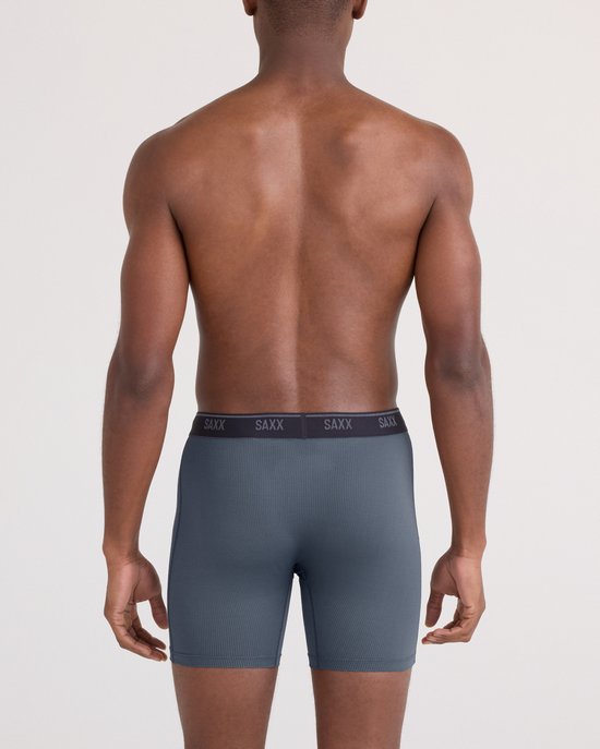 Grijze SAXX boxershort met subtiel ruitpatroon, gedragen door een man van achteren, met SAXX-logo op de tailleband.