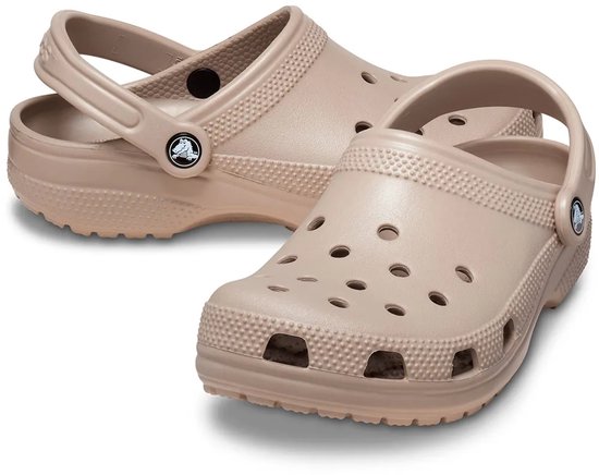 Twee lichtbruine Crocs instappers, de voorste met de neus naar voren en de achterste met de band naar boven.