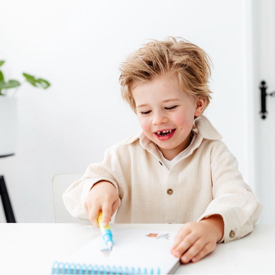 Een lachende jongen met blond haar zit aan tafel en gebruikt een Fien & Teun waterpen op een magisch waterboekje.
