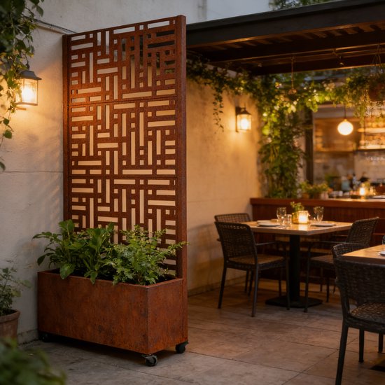 Roestkleurig tuinscherm met plantenbak bij een restaurantterras met tafels.