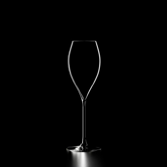 Een helder champagneglas met een slanke stam en een tuitvormige kelk, gecontrasteerd tegen een zwarte achtergrond.