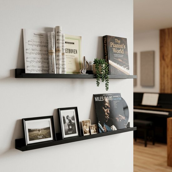 Zwarte zwevende planken met muziekboeken, notities, een vinylplaat en foto's.
