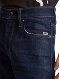 Close-up van de tailleband van een donkerblauwe G-Star jeans met knoop en het G-Star Originals label.