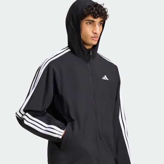 Zwart Adidas windjack met opgezette capuchon, witte mouwstrepen en Adidas-logo, zijaanzicht.