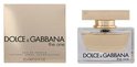 Rechthoekig glazen parfumflesje met gouden dop, gevuld met lichtgele vloeistof. Naast de fles staat de bijpassende verpakking. Eau de parfum, natural spray.