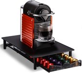 Zwarte capsulehouder met uitschuifbare lade, met daarop een oranje Nespresso apparaat met een glas koffie.