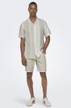 Man in licht beige hemd met verticale strepen, beige shorts.
