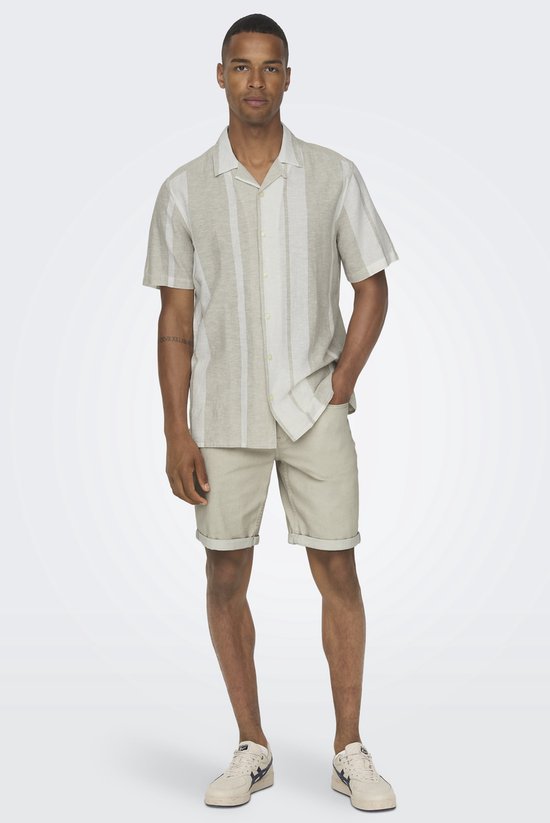 Man in licht beige hemd met verticale strepen, beige shorts.