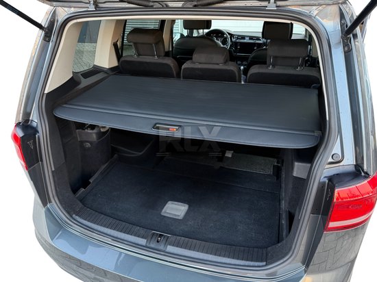 Zwarte oprolbare hoedenplank gemonteerd in de kofferbak van een grijze VW Touran.