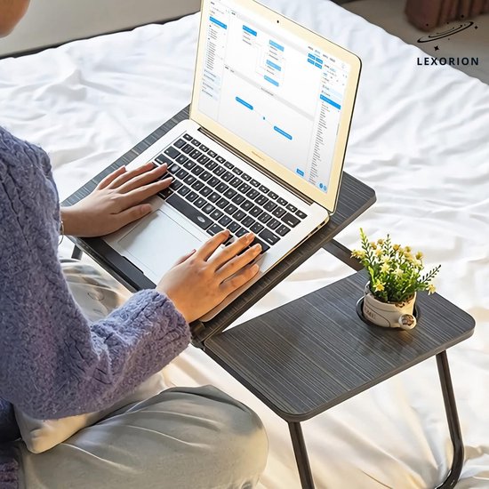 Een persoon gebruikt een laptop op de grijze gestreepte tafel. De tafel heeft een bekerhouder met een plantje.