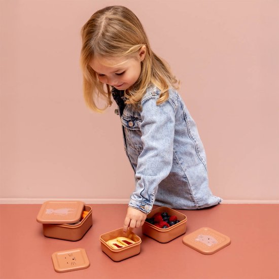 Meisje met sproeten en denim jasje pakt een snack uit een bruin Trixie snackdoosje.
