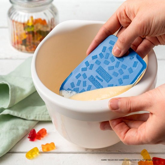 Corne de boulanger bleue avec motif d'ours HARIBO utilisée pour racler la pâte d'un bol.