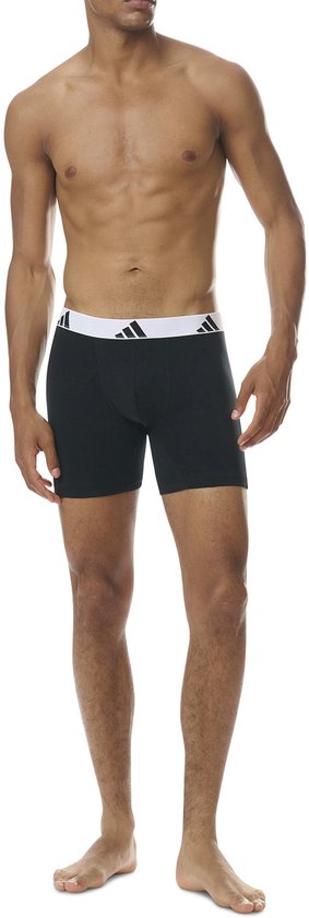 Model in zwarte boxer briefs met witte tailleband en zwart Adidas-logo.