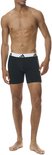 Model in zwarte boxer briefs met witte tailleband en zwart Adidas-logo.