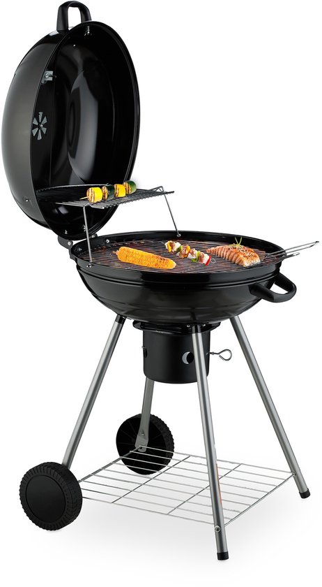 Zwarte kogelbarbecue met open deksel, grillroosters met eten, twee wielen en een opbergrek.