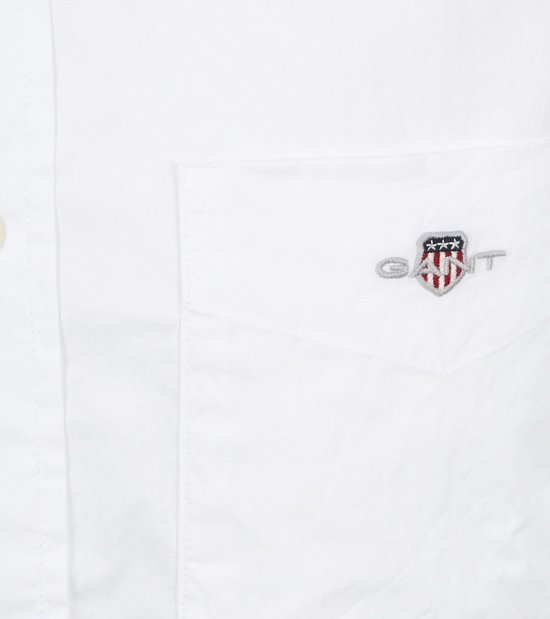 Detail van het Gant logo op de borstzak van een wit overhemd.