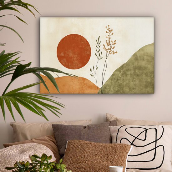 Abstract schilderij met oranje zon, takken en groene heuvels, hangend boven kussens.