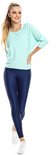 Model in lichtgroene top met driekwart mouwen en navy legging, met witte sneakers.