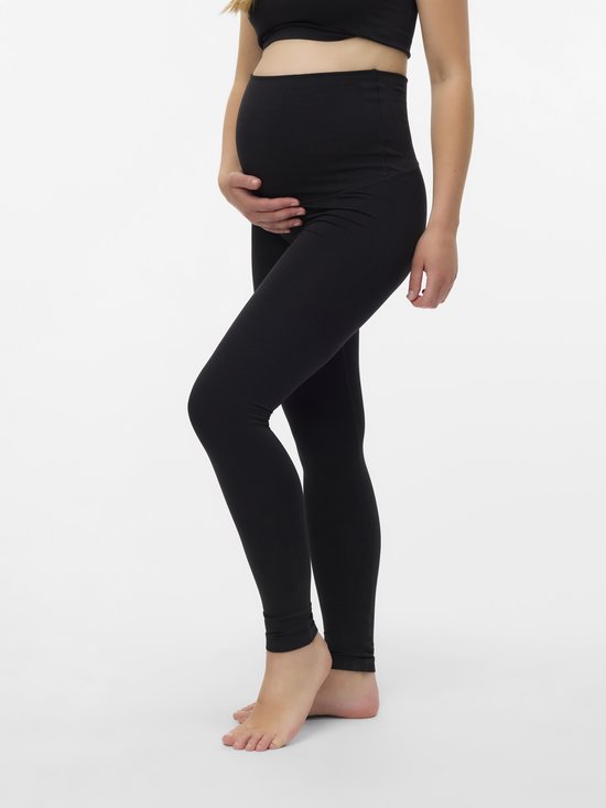 Detailopname van een zwanger model in een zwarte sportbeha en legging, hand op buik.