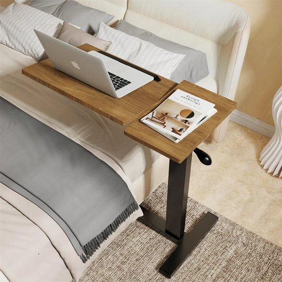 Houten laptoptafel met zwarte voet, geplaatst op een bed met grijze en witte kussens.